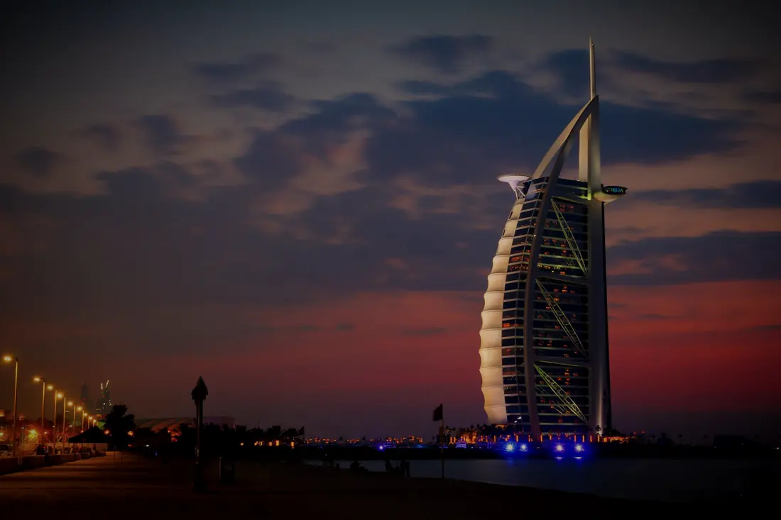 The Burj Al Arab at dusk, lit against a red sky
